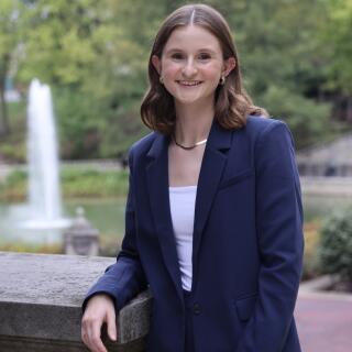 A smiling woman in a white shirt and navy blue jacket