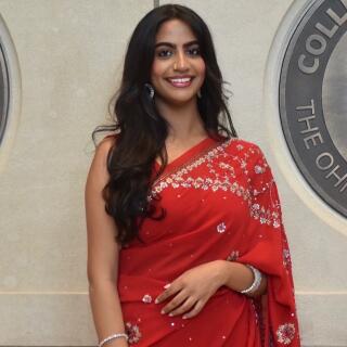 A smiling woman in a red saree with crystal details