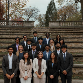 A group of people in business wear stand before outdoor steps