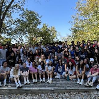 A large group of smiling people sits together outside