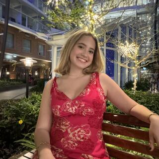 A smiling woman in a red dress sitting on a bench