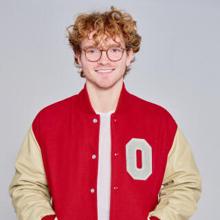 A smiling man in jeans and an Ohio State varsity jacket