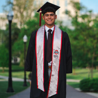 A smiling man in a graduation cap, gown and Ohio State stole