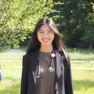 A smiling woman in a black jacket with a stethoscope around her neck