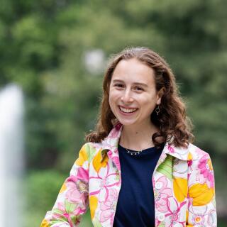 A smiling woman in a navy blue shirt and a bright floral jacket
