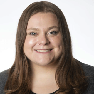 a white woman with brown hair and black blazer smiling