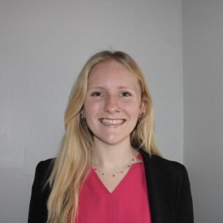 A smiling woman in a red shirt and black jacket