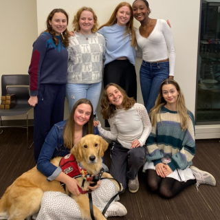 A group of smiling people and a large Golden Retriever pose together