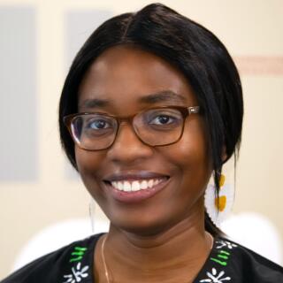 A smiling woman in a black shirt with white and green details and glasses