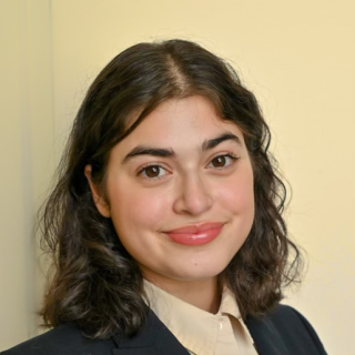 A smiling woman in a yellow shirt and black jacket