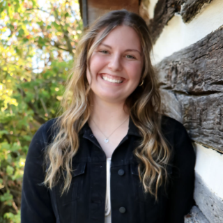 A smiling woman in a white shirt and black jacket
