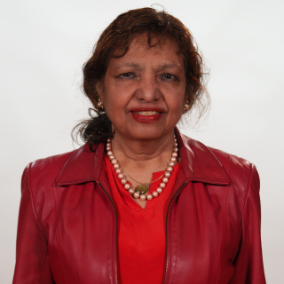 A smiling woman in a red shirt, red jacket and a pearl necklace