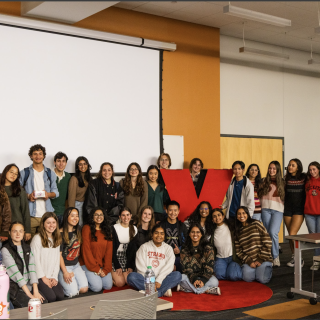 A group of students poses with a large X statue
