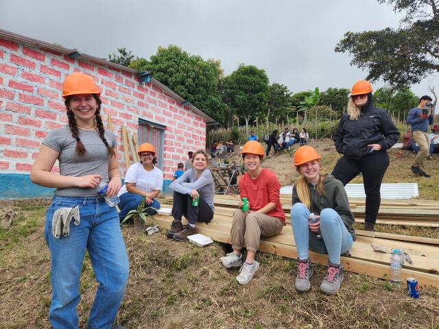 6 volunteers wearing hard hats at construction site in Honduras