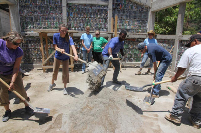 Group of volunteers digging concrete at construction site