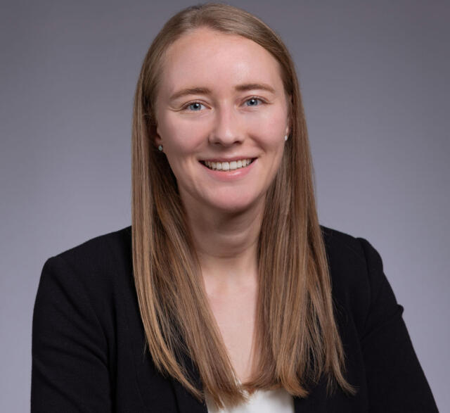 A headshot image of Karissa Libson. She has blonde hair and blue eyes and is wearing a black blazer.