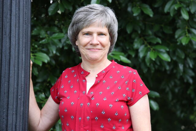 Photo of a white woman with a gray bob and a red shirt
