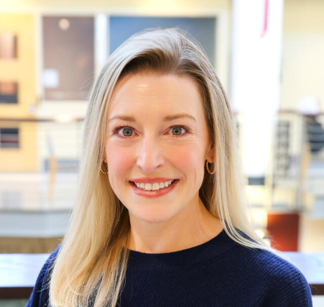 photo of smiling white woman with blonde hair wearing a blue sweater