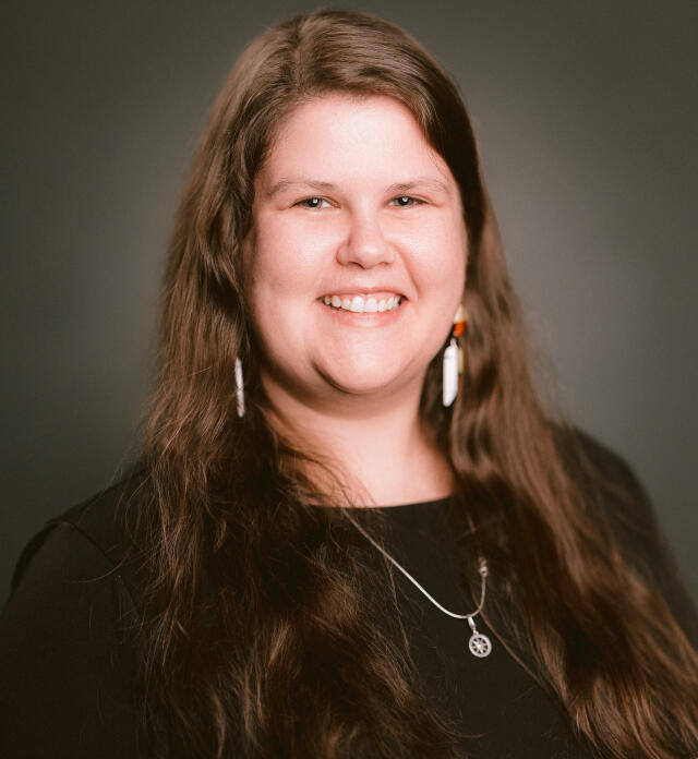 A headshot image of Madison Eagle. She has brown hair and green eyes, and wears a black top.