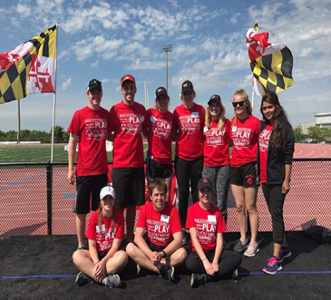 Group of college student volunteers wearing red t-shirts in front of running track