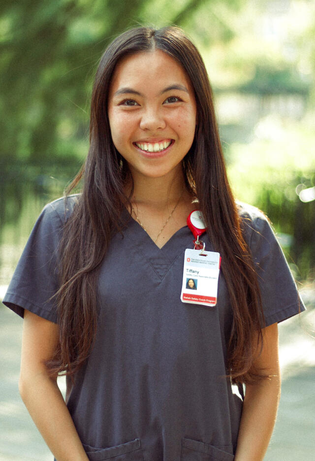 An image of Tiffany Nguyen outdoors. She has long, brown hair and wears an OSU medical uniform.