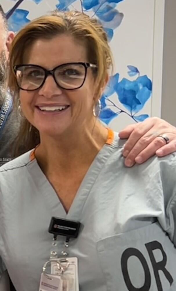 Regina smiling in OR scrubs at camera.