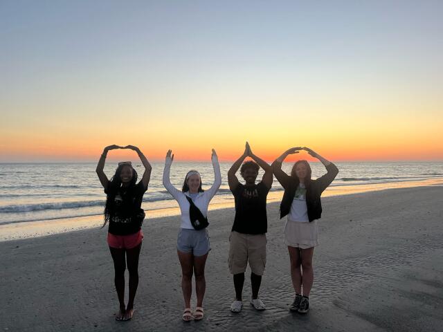 Four students pose for OHIO on the Florida Coastline at sunset.
