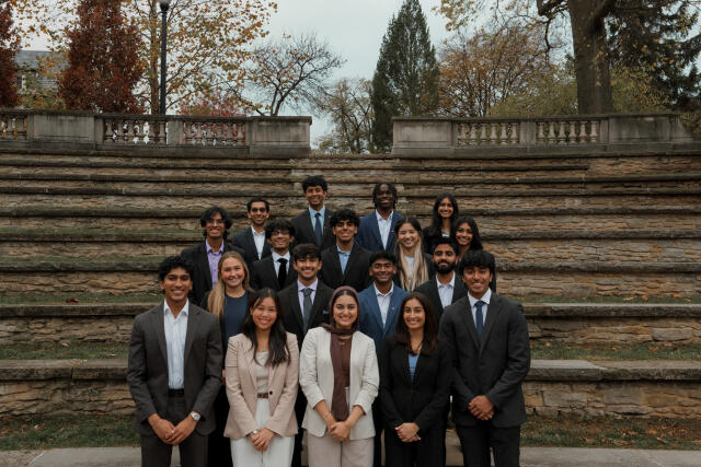 A group of people in business wear stand before outdoor steps
