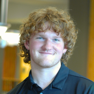 A man in a black polo smiles