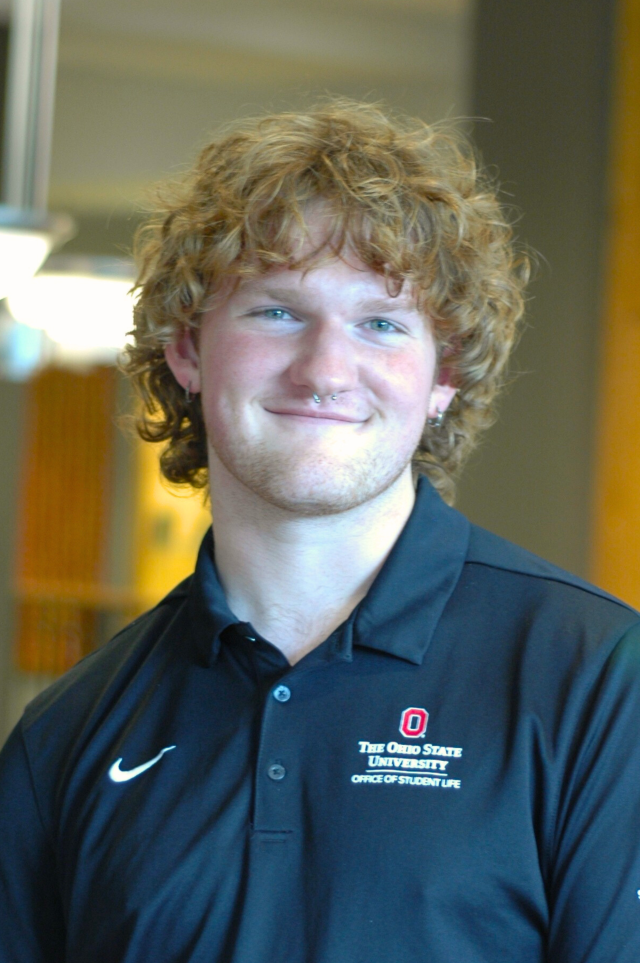 A man in a black polo smiles