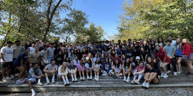 A large group of smiling people sits together outside