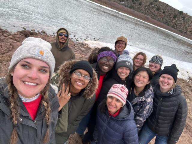 11 volunteers gathered in front of river/stream in Colorado