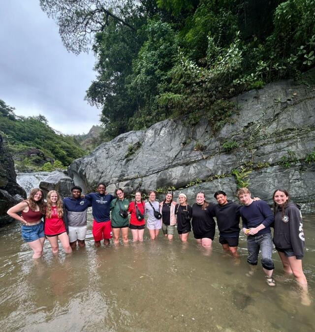 13 Members of a Buck-I-SERV Trip to the Dominican Republic pausing for a photo in a river