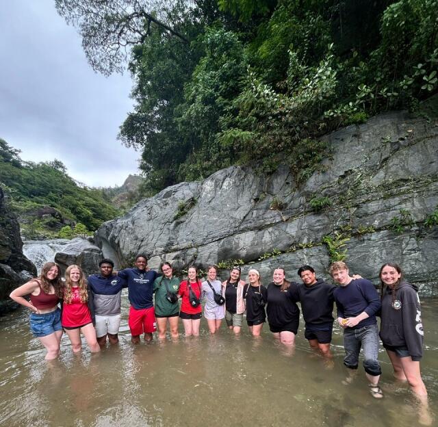 Students pose for a photo in a river surrounded by rock formations