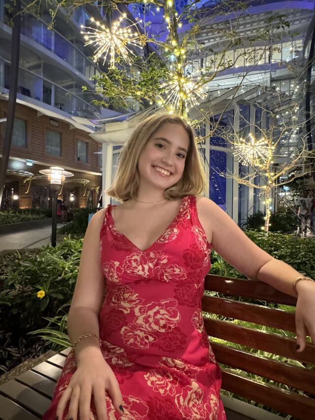 A smiling woman in a red dress sitting on a bench