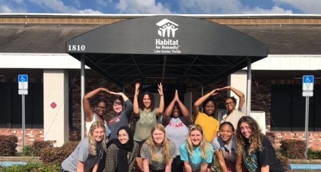 Group of 12 college students posing in front of Habitat for Humanity Lake Sumter sign
