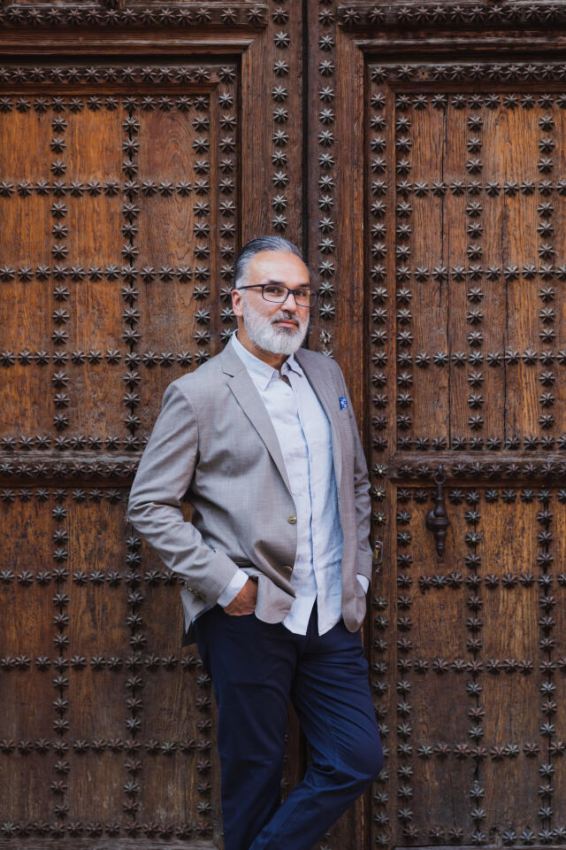 Photo of a latino man with grey hair wearing a suit