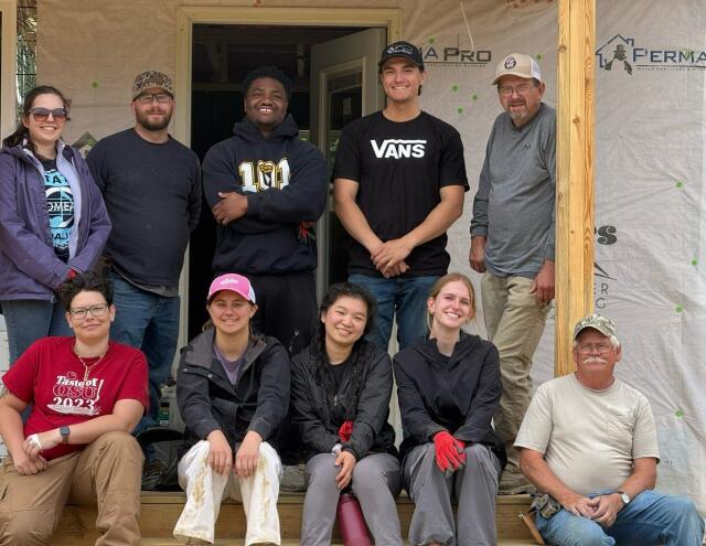 Students and Frontier Housing staff pose for photo on the front porch of a new home build
