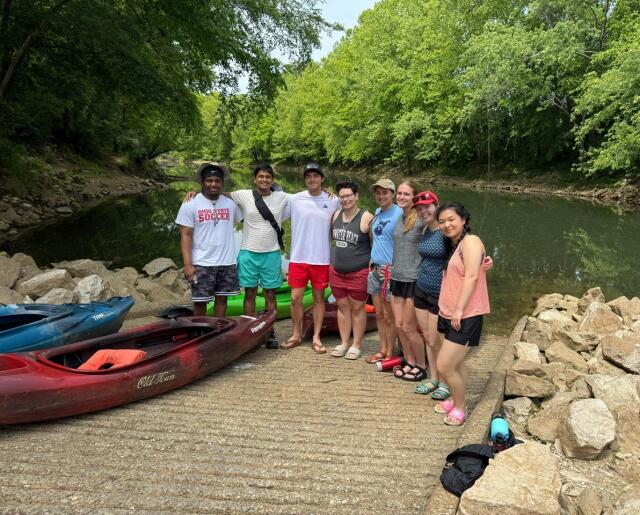 Students pose in front of kayaks on a river in Kentucky
