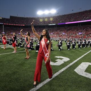 A female student in a homecoming court sash on a football field