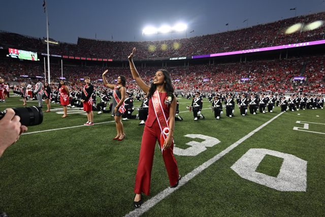 A female student in a homecoming court sash on a football field