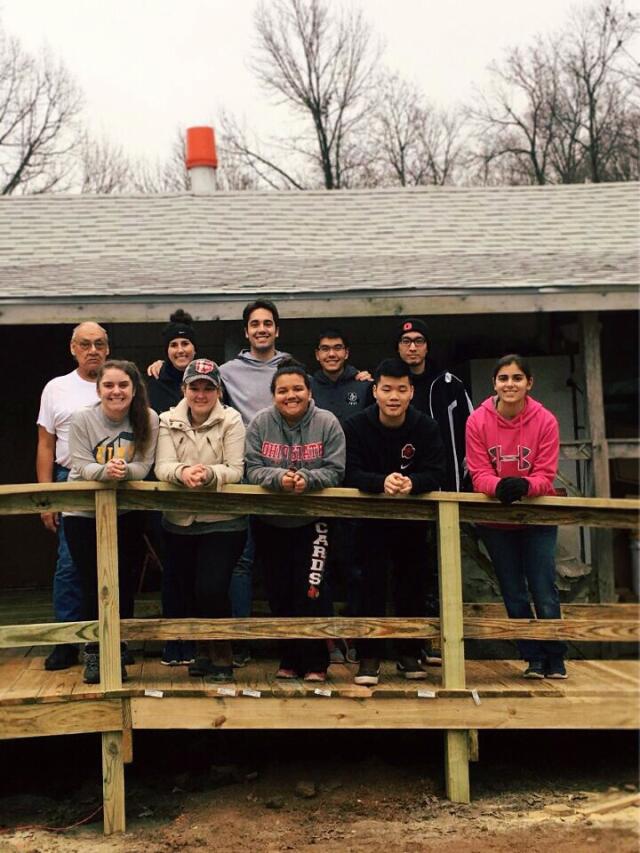 10 adult volunteers standing outside on deck/ramp during service trip