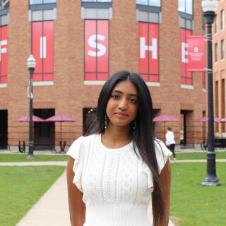 A female student in white outsite of a building
