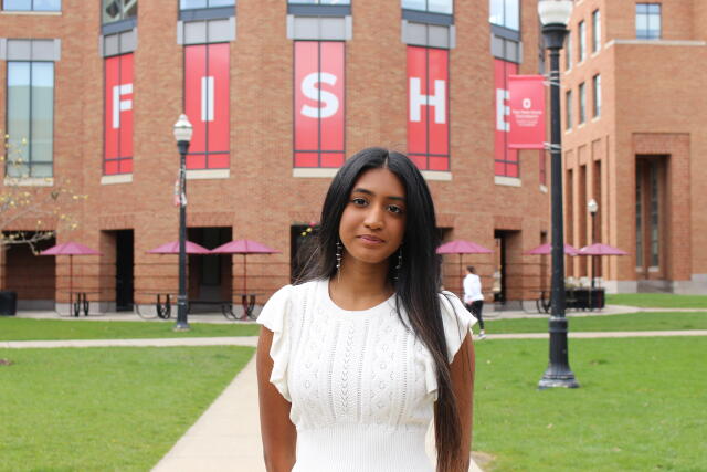 A female student in white outsite of a building