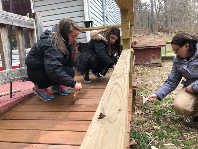 3 student volunteers painting wheelchair accessible ramp