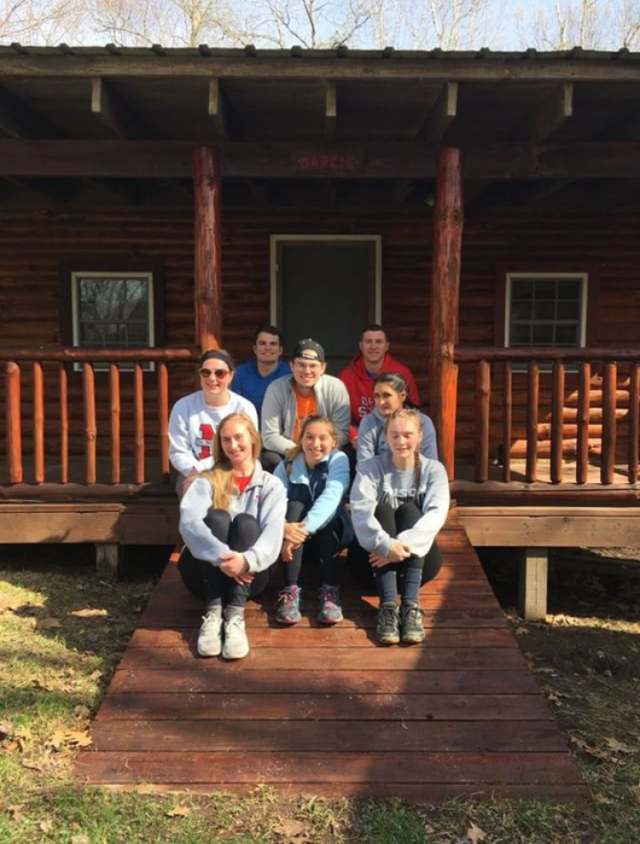 Buck-I-SERV alternative break participants seated in front of cabin at One Heartland