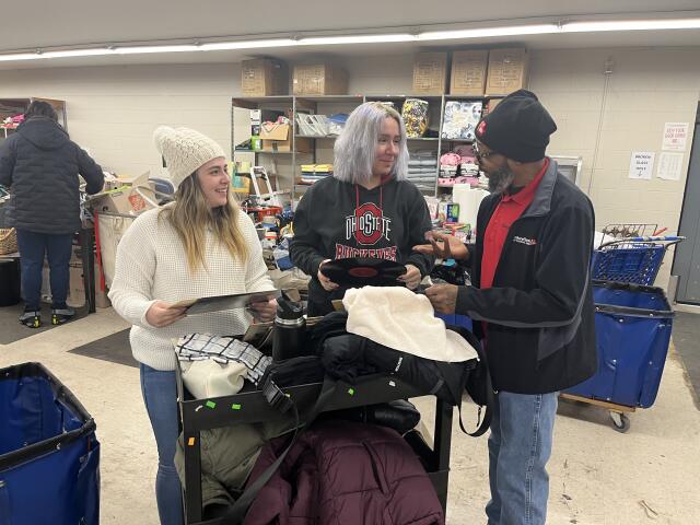 Two student volunteers sorting donations with a community partner.