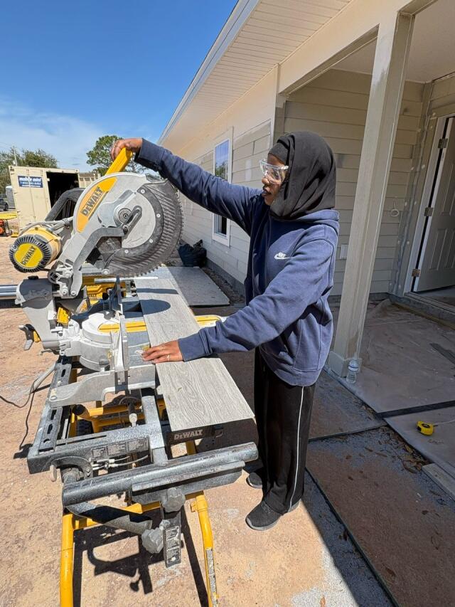 A student working to cut a board using a chop saw