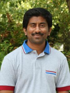 Veeramani smiling at the camera outside.