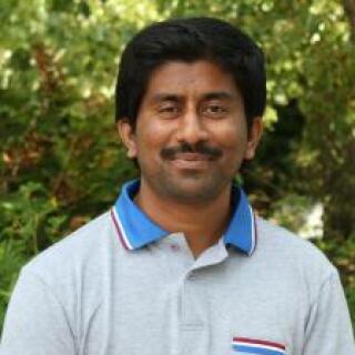 Veeramani smiling at the camera outside.